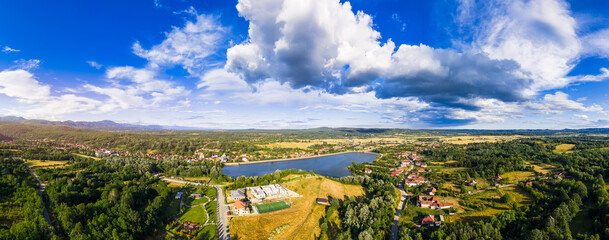 Scenic view of Tismana village in Gorj County Romania under a bright blue sky with fluffy clouds. A stunning landscape captures the beauty of Tismana village in Gorj County. Tismana, Romania.