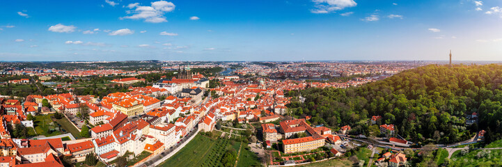 Fototapeta premium Panoramic view of Prague featuring historic buildings and vibrant rooftops on a sunny day in summer. View of Prague, Czech Republic, showcasing Prague iconic architecture and red-tiled roofs, Czechia