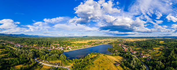 Scenic view of Tismana village in Gorj County Romania under a bright blue sky with fluffy clouds. A stunning landscape captures the beauty of Tismana village in Gorj County. Tismana, Romania.