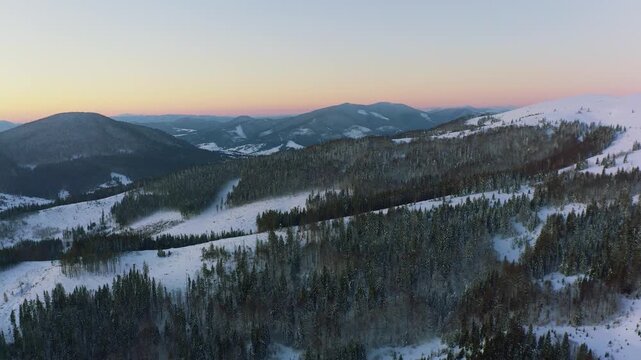 An extraordinary valley with hills and mountains covered with fir forests against the backdrop of a bright fiery sunset