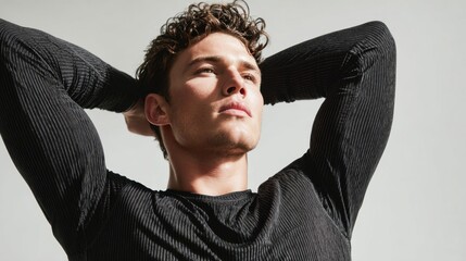 Young man posing, arms behind head, looking up