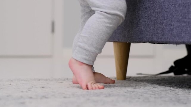 Baby boy takes first steps and learns how to walk barefoot at home. Slow motion