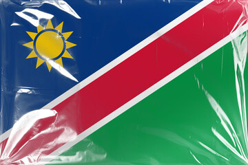 Flag of Namibia Covered with Transparent Plastic Wrap, Showcasing Its Blue, Red, White, and Green Colors Along with the Yellow Sun Emblem, Creating a Textured Surface