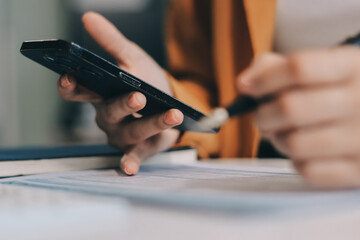 Business woman using calculator for do math finance on wooden desk in office and business working background, tax, accounting, statistics and analytic research concept.