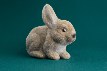 Adorable brown fuzzy rabbit figurine sits on a dark teal background. Perfect for Easter, spring, or pet-related themes.