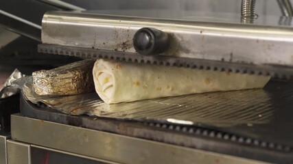 Watch a skilled chef expertly prepare succulent shawarma on the grill. The fragrant spices and tender meat create mouthwatering aromas, making every bite a delight at this busy kitchen counter.