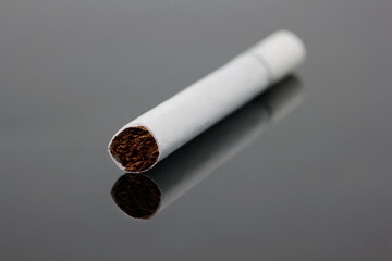 Close-up of cigarette  with dried tobacco leaves on black background
