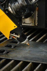 Close-up of fiber laser cutter nozzle and head assembly during high-speed sheet metal profile cutting on CNC flatbed table