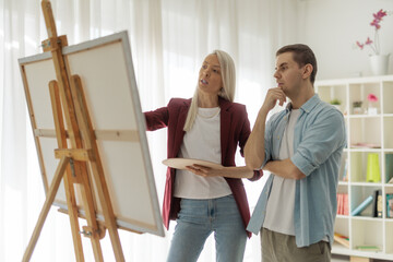 Young man and woman discussing a canvas painting
