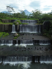 Majestic Mountain And Tiered Waterfalls Surrounded By Lush Green Jungle Landscape With Volcanic Peak In Distance