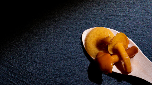 setas en una cuchara de madera en un plato, pholiota nameko, com&uacute;nmente conocido como nameko, hongo basidiomiceto de la familia Strophariaceae. Su seta es peque&ntilde;a, con un sombrero de color &aacute;mbar 