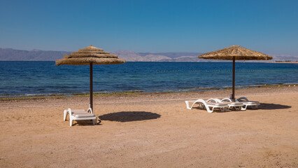 Two sun umbrellas on the sand beach in Aqaba - Jordan