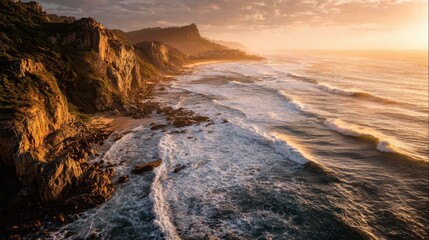 Rugged cliffs meeting ocean waves at sunset