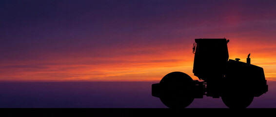 Silhouette of a heavy road roller machine on a construction site against a dramatic purple and orange sunset sky.