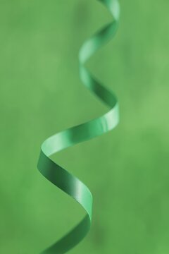 Cinta verde satinada sobre fondo a tono, Primer plano de serpentina verde sobre superficie lisa, Mockup para dise&ntilde;o con tem&aacute;tica del d&iacute;a de San Patricio