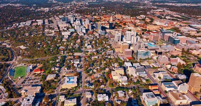 Beautiful sunlit panorama of a vast city with lots of lush greenery. Drone flight over the cityscape of Austin, Texas, USA.