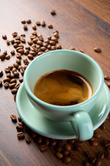 A cup of coffee viewed from above. Coffee beans are scattered around it. 