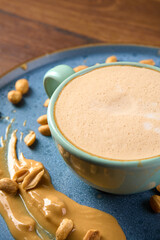 a cup of cappuccino sits on a plate with peanuts and peanut butter                               