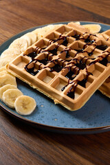 Viennese waffles covered in chocolate lie on a plate with bananas                               
