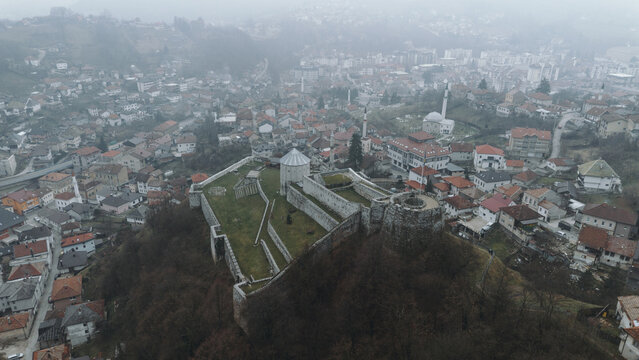 Aerial view of Travnik Fortress overlooking the town and surrounding hills, showing historic stone walls, green courtyards and misty mountain landscape from above. Amazing Bosnia and Herzegovina