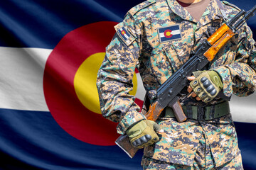 Naklejka premium Colorado US state flag with soldier holding assault rifle in front of it