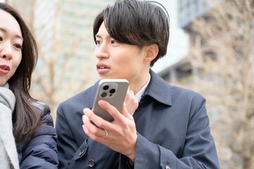 オフィス街でスマホを使用する日本人男女