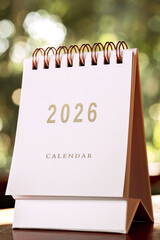 Small white calendar year 2026 on wooden table, with copy space.