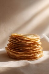 Stack of golden, crispy pancakes arranged neatly on a soft surface, illuminated by warm sunlight, evoking the festive spirit of spring celebrations and traditional culinary delights