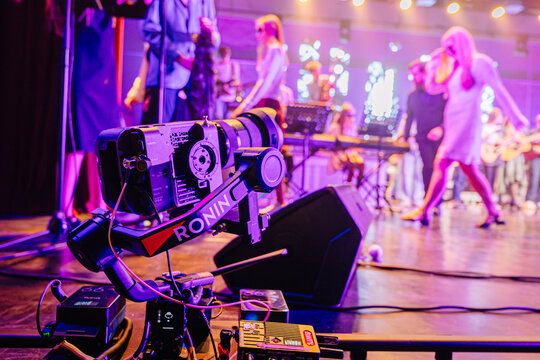 Valmiera, Latvia - December 29, 2025: Camera equipment on stage capturing live performance with musicians and singers in vibrant lighting atmosphere