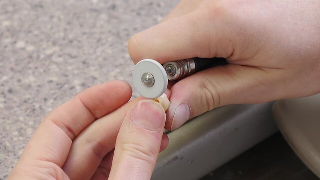 Dental technician polishing ceramic material of artificial tooth crown of dental implant in dental laboratory. dentist using rotary tool with fine bur to polish freshly milled veneer. Concept of
