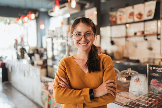Confident female cafe owner standing with arms crossed inside modern coffee shop. Authentic small business portrait ideal for branding, Authentic entrepreneur portrait perfect for startup branding