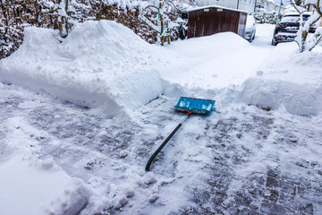 Close up view of snow shovel lying on cleared paved walkway after heavy winter snowfall. Sweden.