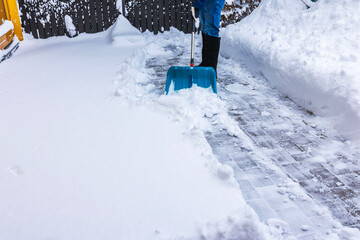 Close up view of person clearing snow from villa walkway using shovel during cold winter day. Sweden.