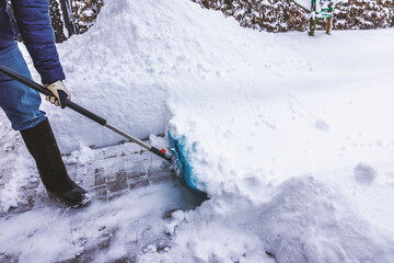 Close up view of man shoveling deep snow from paved walkway near house after heavy snowfall. Sweden.