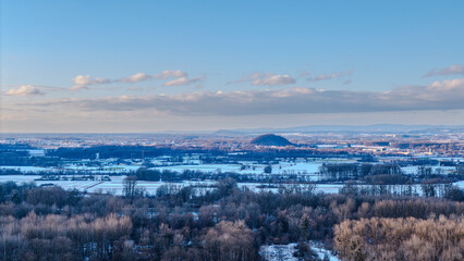 Blick auf eine winterliche Landschaft mit B&auml;umen und H&uuml;geln in der Ferne