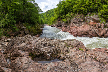spring is a granite canyon of a mountain river, walking along a stone riverbed with a rapid flow of water