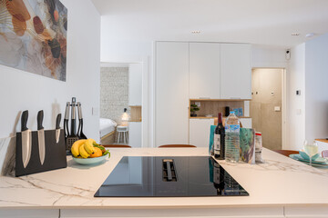 Modern kitchen island with marble surface, cooking essentials and view into cozy bedroom