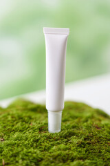 Tubo de crema cosm&eacute;tica blanca sobre musgo verde, Crema facial hidratante en envase minimalista, Mockup para marca de cosm&eacute;tica natural