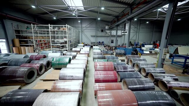 Many metal coils for roofing sheet production are stored and kept in the factory warehouse. large metal coil for roofing sheet production, handling heavy industrial