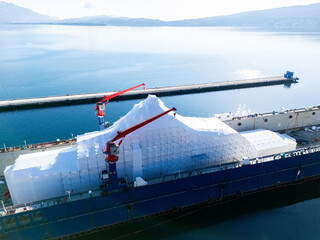 Aerial view of a luxury yacht refit, repair, service and maintenance in a floating dock at a marina.