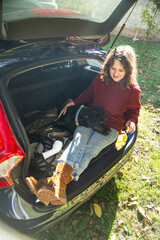Woman with her dog sitts into trunk of electric car