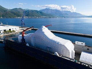 Aerial view of a luxury yacht refit, repair, service and maintenance in a floating dock at a marina.