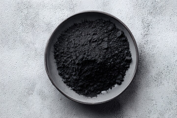 Black activated charcoal powder in a ceramic bowl for detox