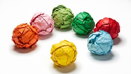 Collection of seven brightly colored paper balls crumpled into tight spheres arranged on a clean white surface emphasizing texture and variety.