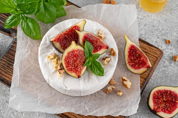 Camembert, bree cheese, walnuts, fresh figs and honey on a cutting board on a concrete background. Charcuterie Board. Top view