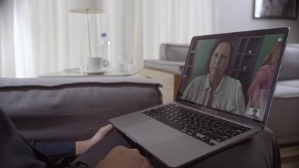 Person sitting on a sofa using a laptop for a video call with a mature woman, remote communication and online meeting concept. - Powered by Adobe