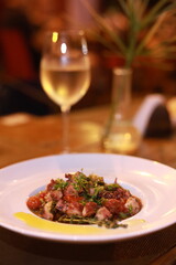 Vinagrete de polvo harmonizado com vinho branco, servido em mesa externa de restaurante em Paraty, com atmosfera acolhedora e luz noturna.