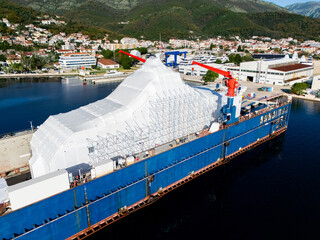 Aerial view of a luxury yacht refit, repair, service and maintenance in a floating dock at a marina.