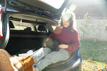 Woman with her dog sitts into trunk of electric car