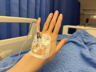 Patient Hand with IV Drip in Hospital Bed. Medical treatment, healthcare, hospitalization, recovery,  emergency and clinical care concept